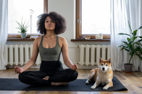 A woman practices yoga at home with her Shiba Inu dog, embracing a relaxing morning.